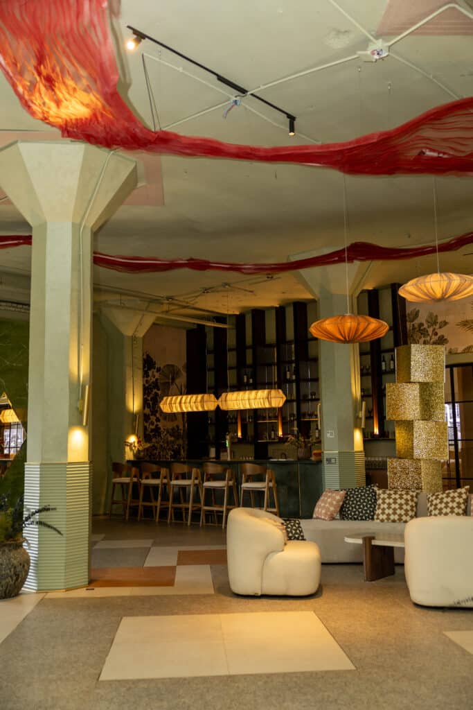 Interior del bar con columnas, luminarias suspendidas y sofás curvos blancos